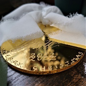 Flat, circular acrylic Christmas ornament with engraving in modern calligraphy and block lettering