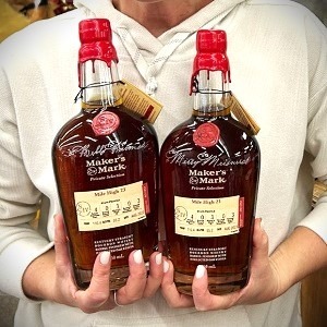 A customer holding two Maker's Mark bottles with personalized etching on the bottles in Spencerian script