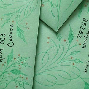 A pile of green envelopes with holly and pine flourishes