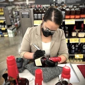 Melissa of Mellie Rose Design LLC engraving a Maker's Mark bottle with a hand-held engraving machine